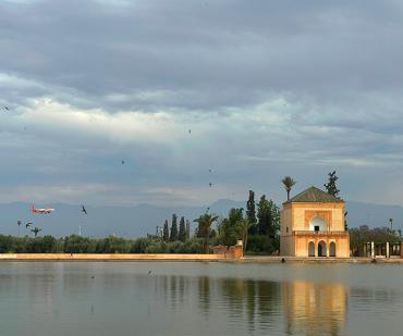 Pavillon de la Ménara à Marrakech avec les montagnes de l’Atlas en arrière-plan, point de départ idéal pour un circuit de 7 jours dans le sud marocain