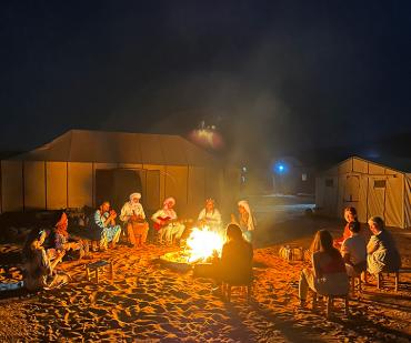 Soirée autour du feu dans un bivouac berbère traditionnel au cœur du désert marocain, expérience authentique d’un circuit désert au départ de Marrakech