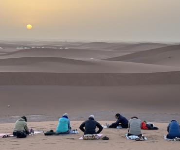 Séance de yoga au lever du soleil sur les dunes du désert marocain lors d’un stage bien-être