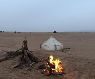 Bivouac traditionnel avec feu de camp dans le désert marocain pendant un circuit nomade de 5 jours