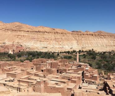 Village berbère traditionnel en terre cuite entouré de palmeraies sur la route du désert depuis Marrakech